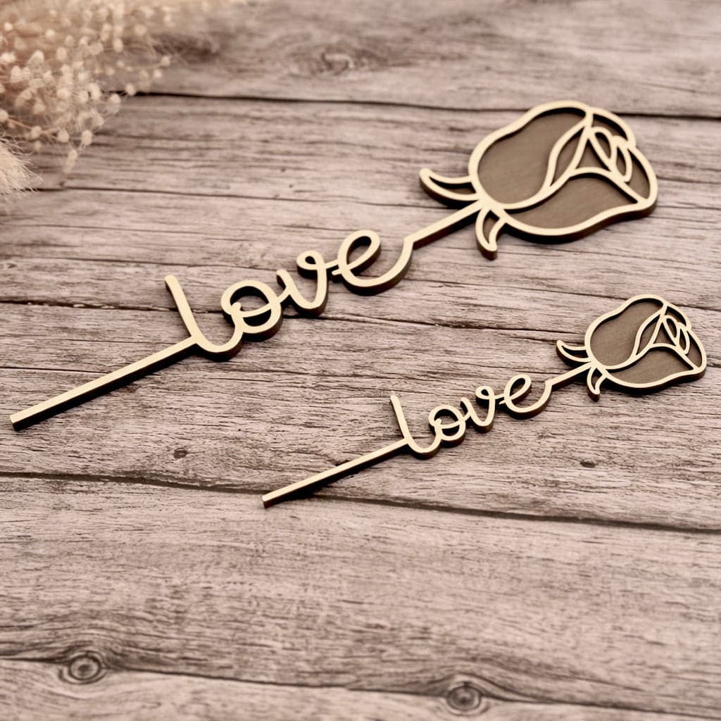 Zwei Holzrosen liegend auf einem Tisch – auf dem Stil ist das Wort love eingearbeitet. Die Rosen haben unterschiedliche Größe und sind passend für den Valentinstag