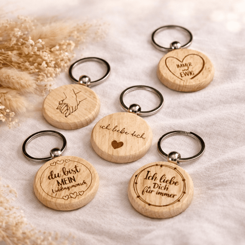 Mehrere runde Holz Schlüsselanhänger, auf einem dekorierten Tisch liegend, mit unterschiedlichen Valentinstags-Botschaften wie ich liebe dich für immer